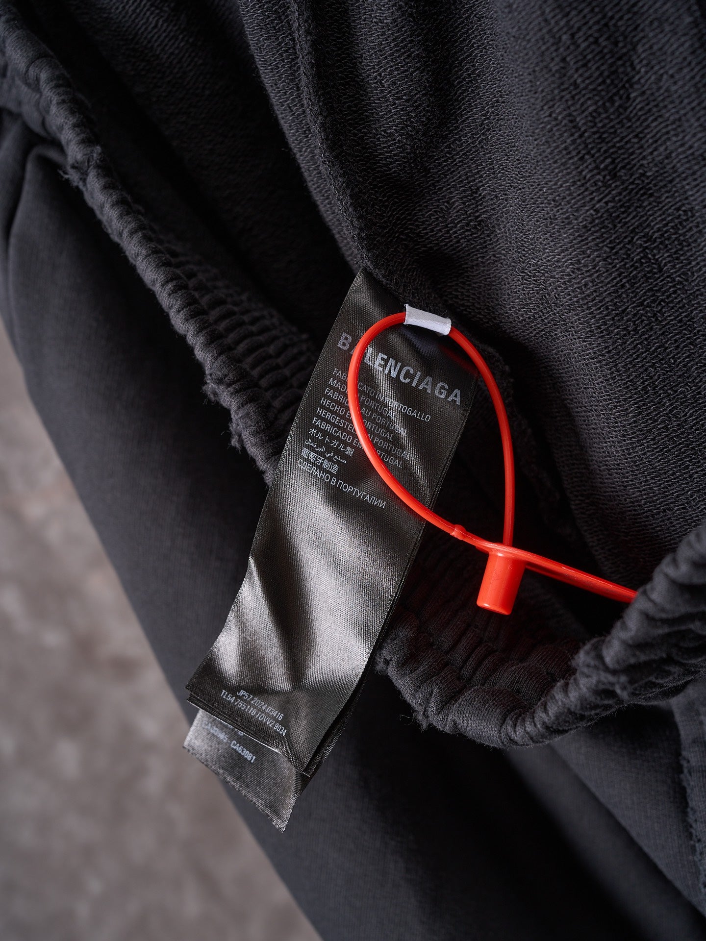 Black shorts closeup with inner tag and red security tether near hem.