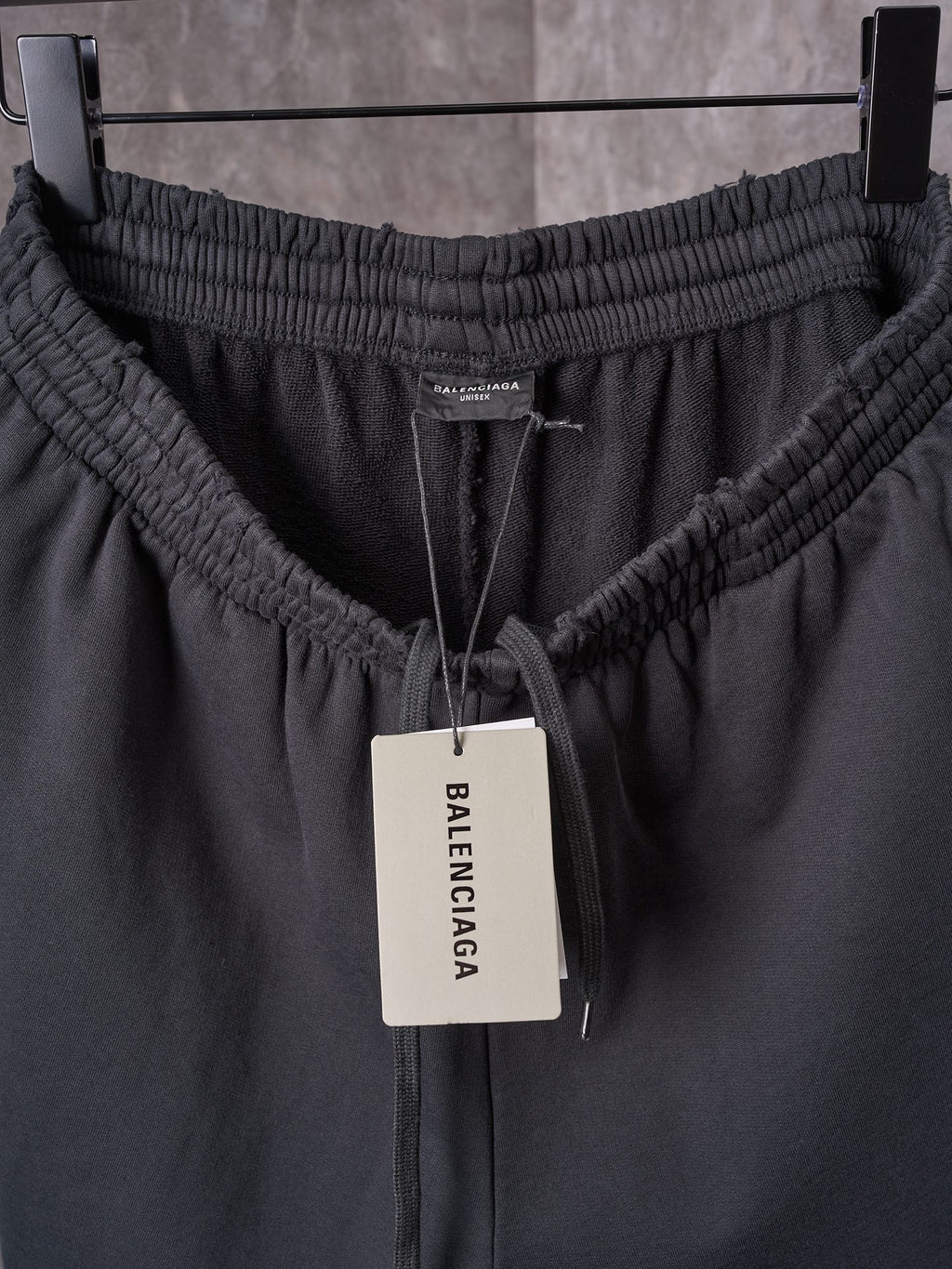 Black shorts waistband with elastic channel, drawstring, and center brand tag.