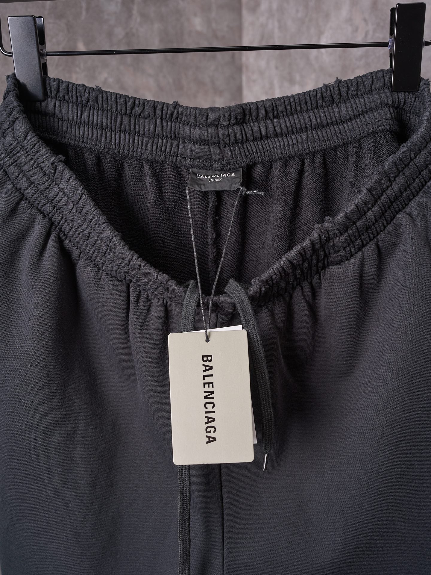 Black shorts waistband with elastic channel, drawstring, and center brand tag.
