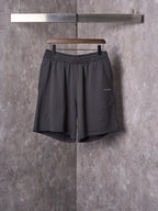 Black drawstring shorts with elastic waistband and scalloped hem trim.