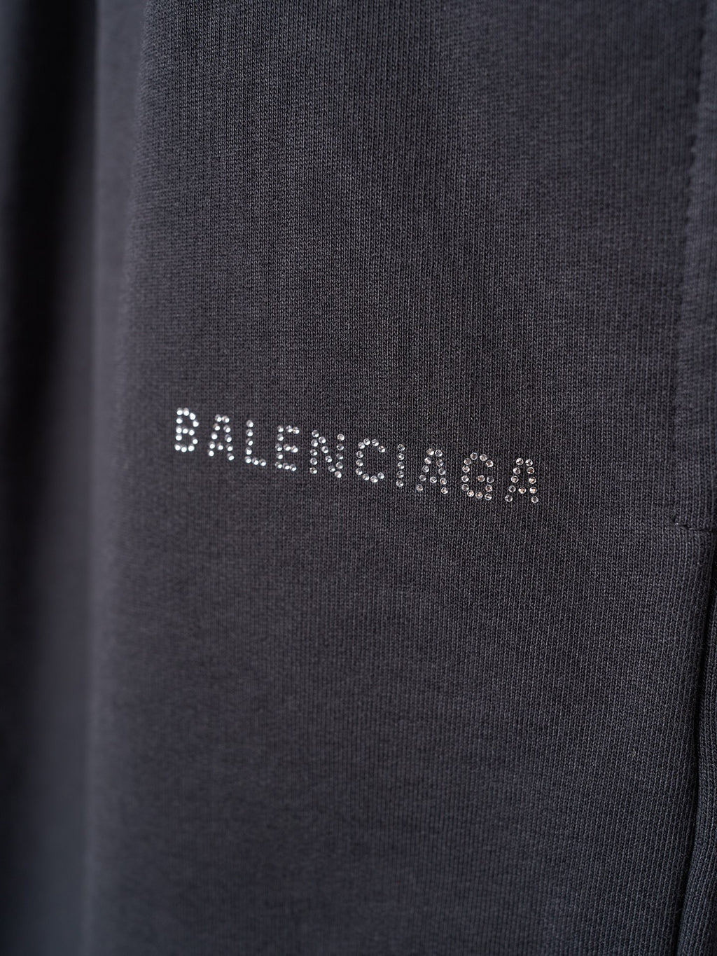 Black shorts fabric closeup with small white BALENCIAGA lettering on the leg.