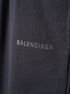 Black shorts fabric closeup with small white BALENCIAGA lettering on the leg.