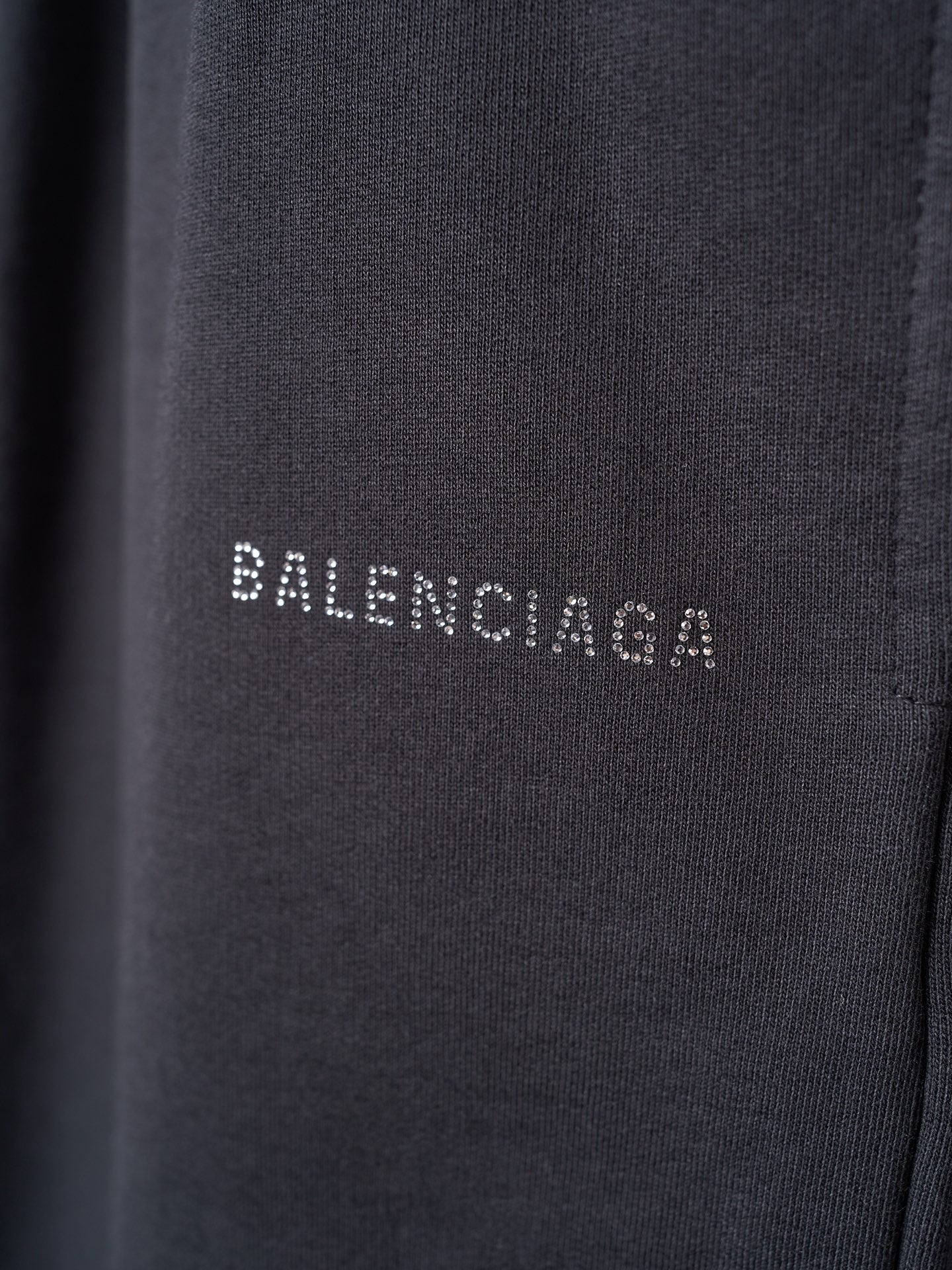 Black shorts fabric closeup with small white BALENCIAGA lettering on the leg.