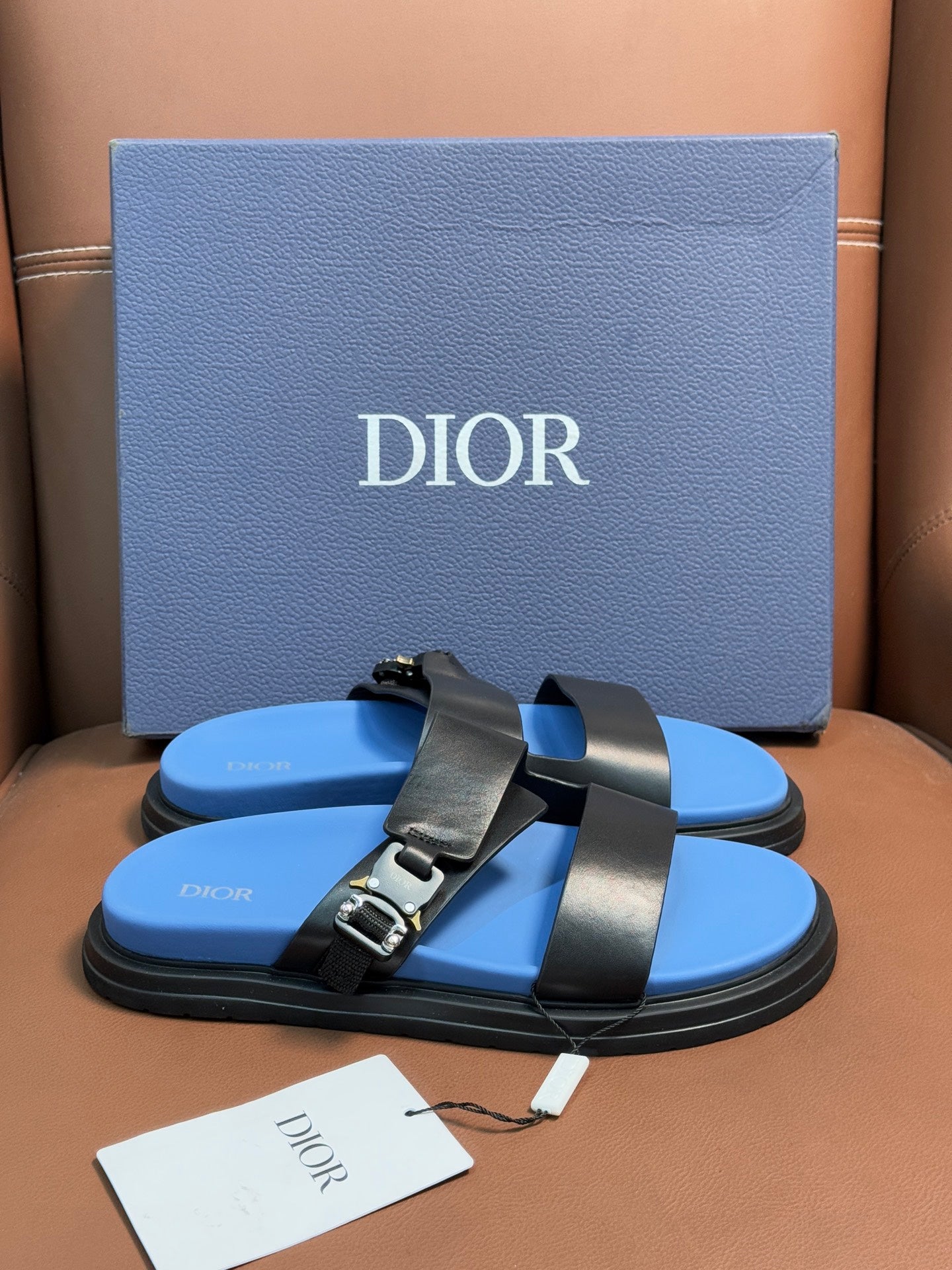 Dior slide sandals, black two-strap design with gold buckle on blue footbed