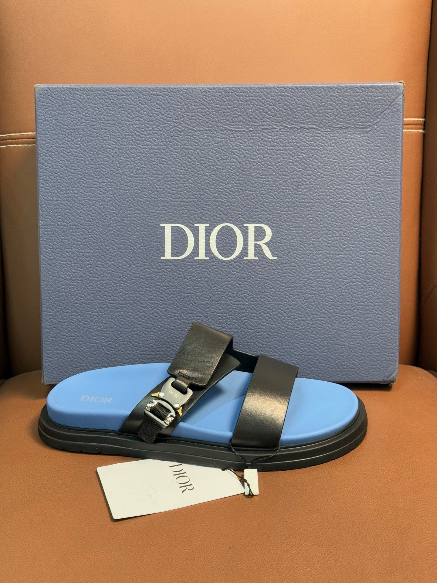 Dior slide sandals with black leather straps and gold buckle detail, blue footbed