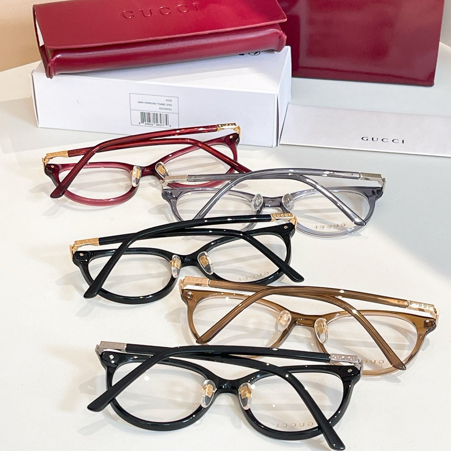 Gucci glasses set with red, black, and bronze frames and clear lenses