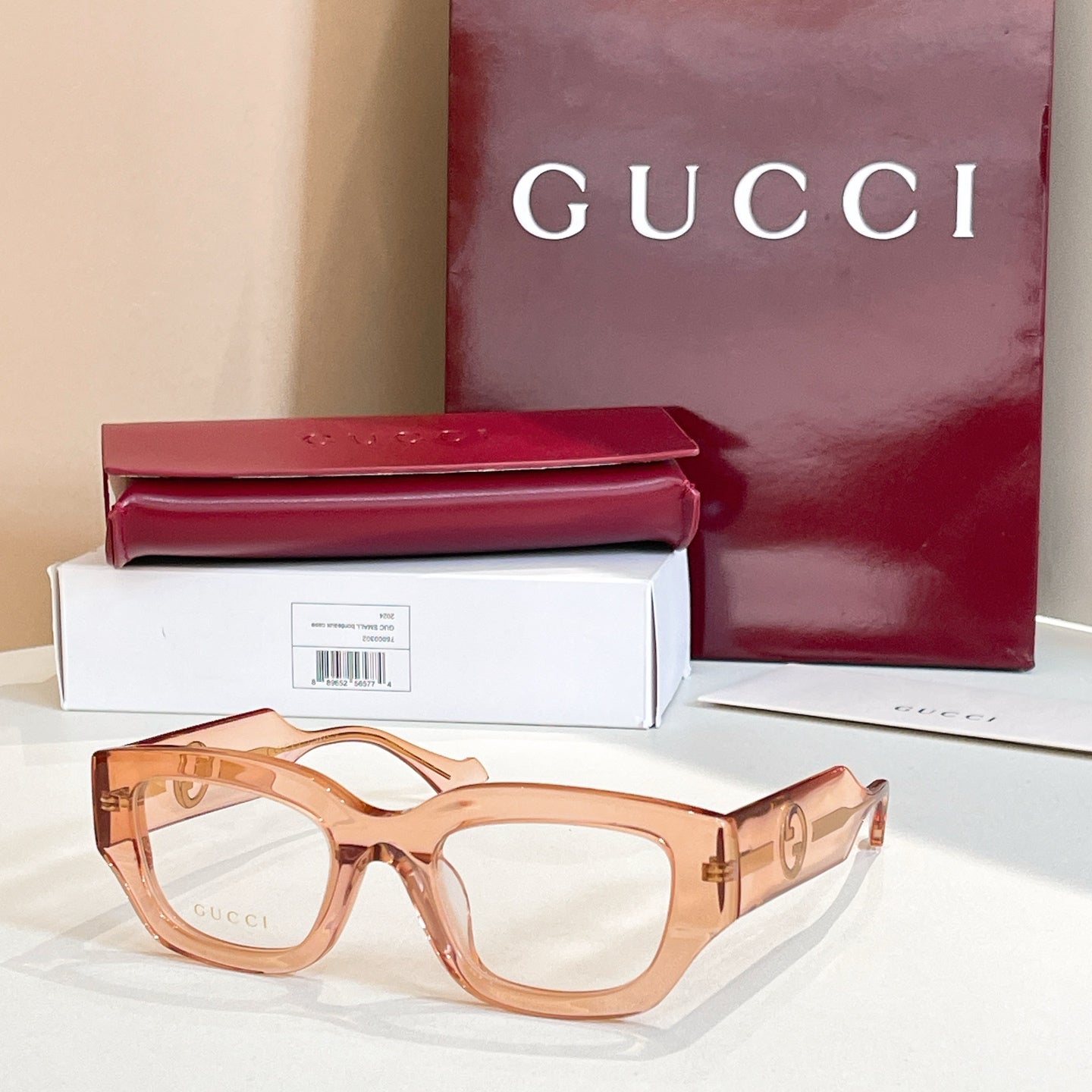 Eyeglasses with translucent peach-pink frames and gold-tone side GG logo detail