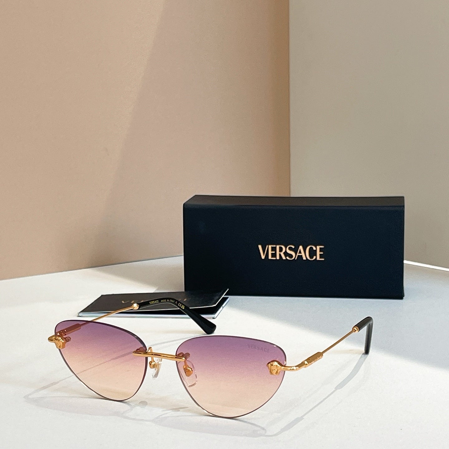 Versace sunglasses with purple tinted lenses and gold frame, round cat-eye style
