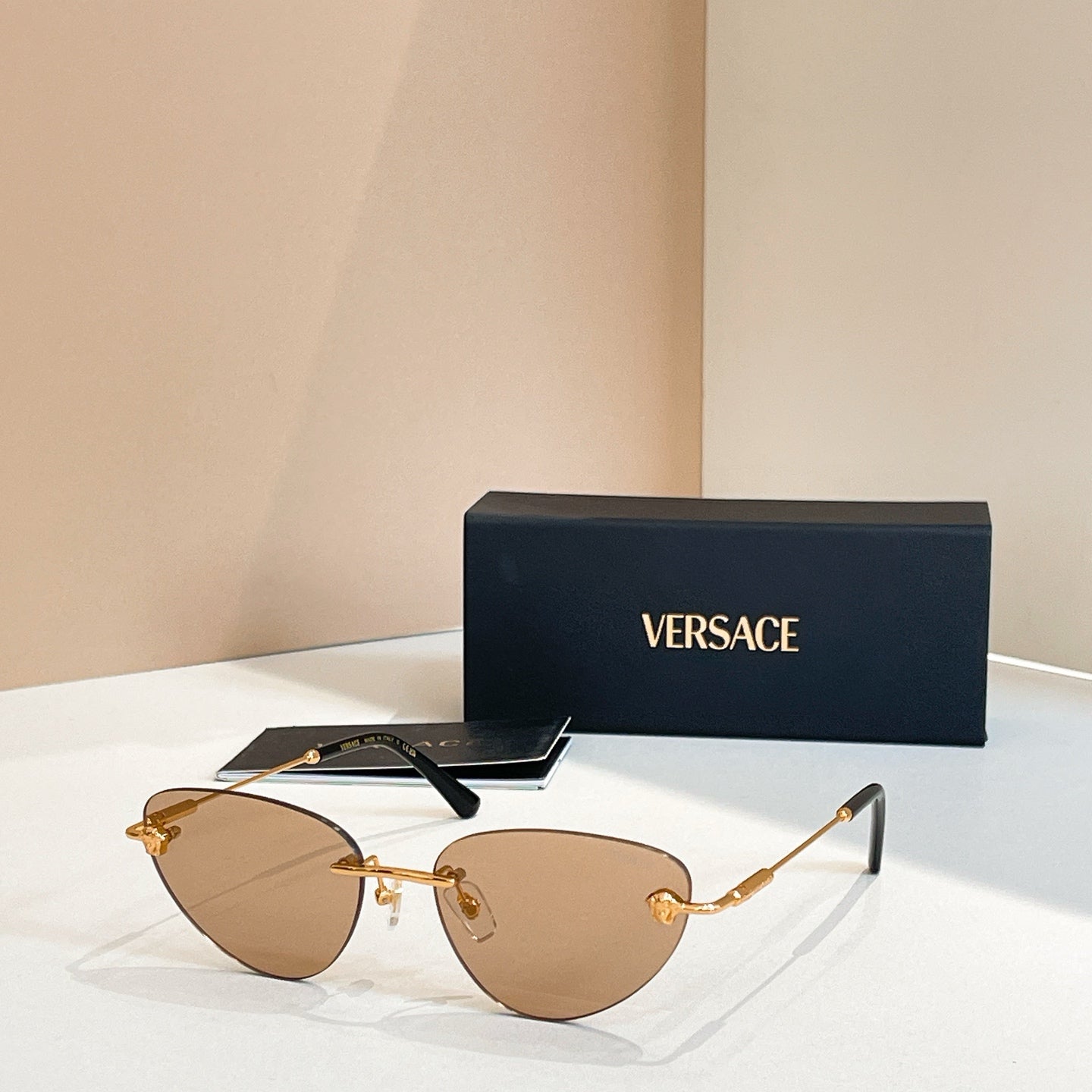 Versace sunglasses with brown/tan tinted lenses and gold frame, round cat-eye style