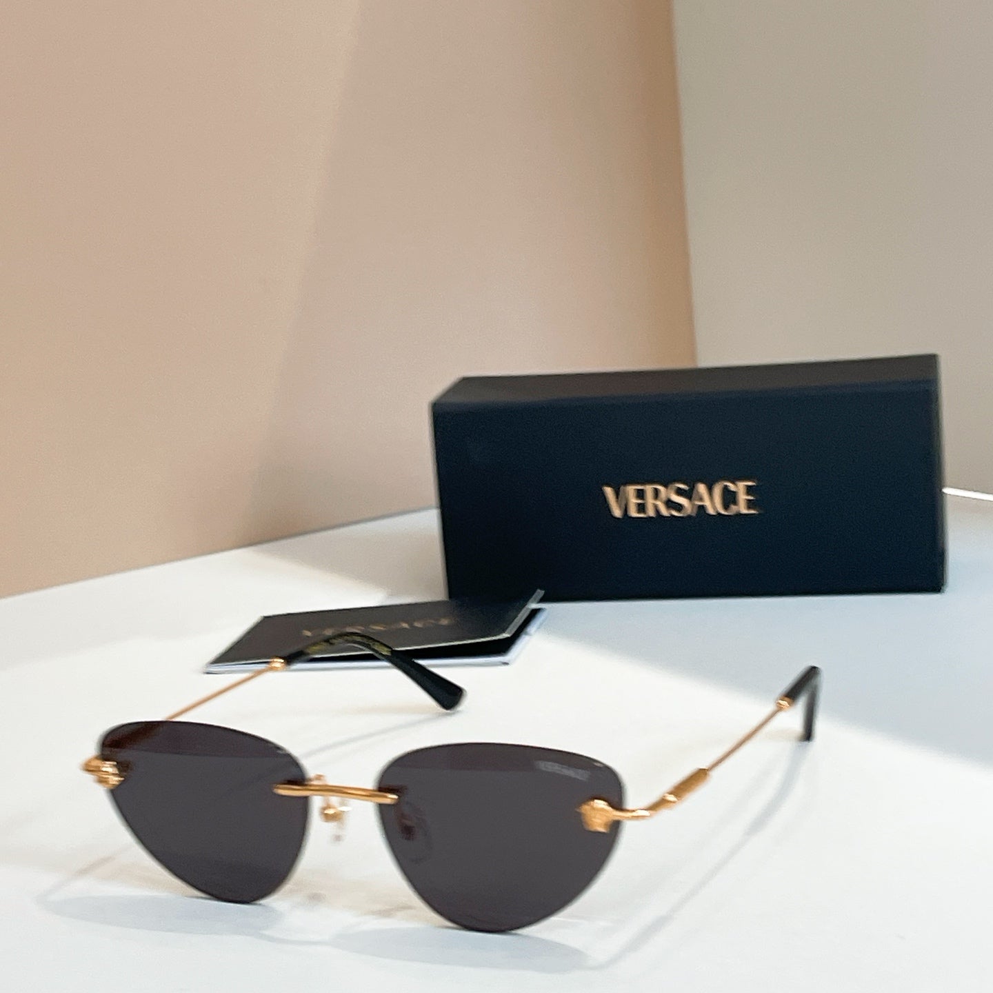 Versace sunglasses with dark tinted lenses and black-and-gold frame, V logo on arms