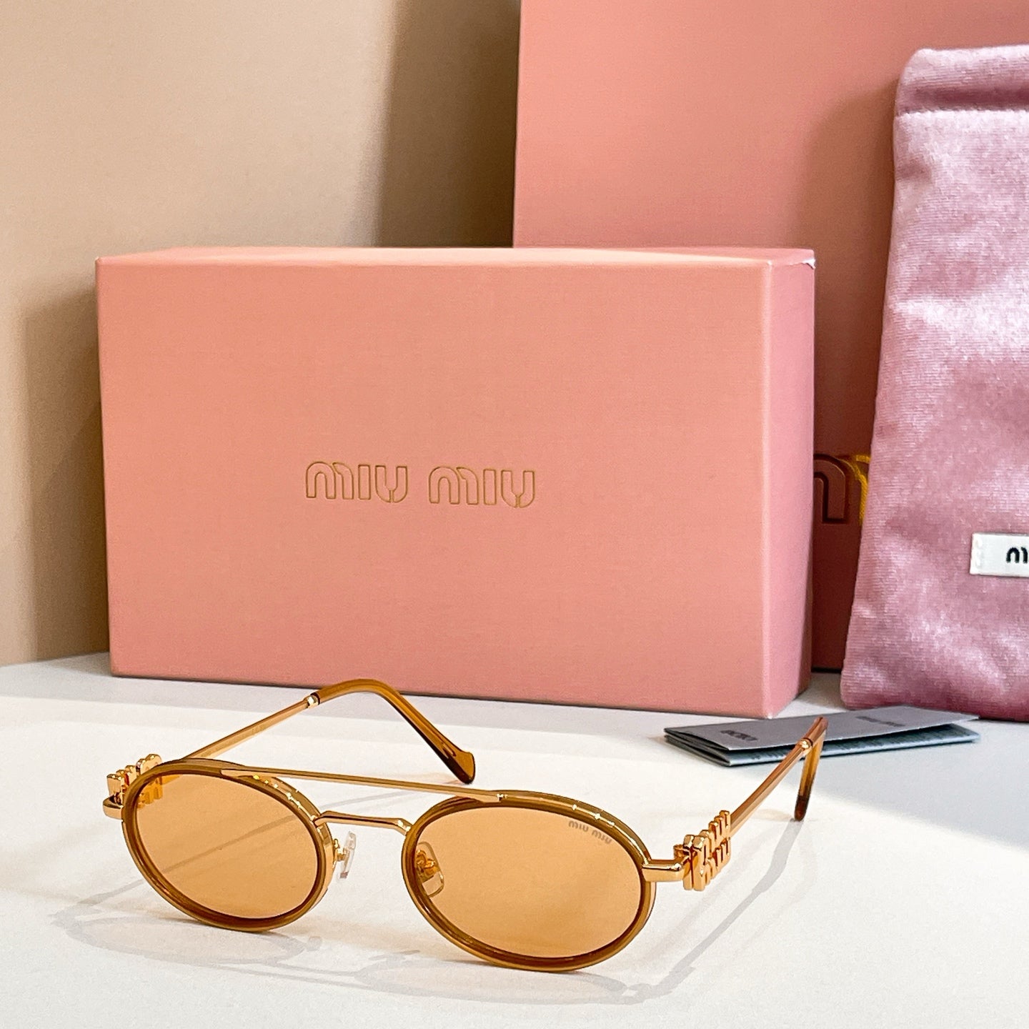 Miu Miu round sunglasses with amber lenses and gold frame, front angle