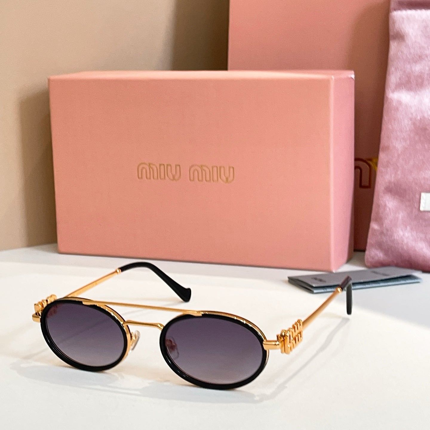 Miu Miu round sunglasses with gold frame, black arms, dark tinted lenses