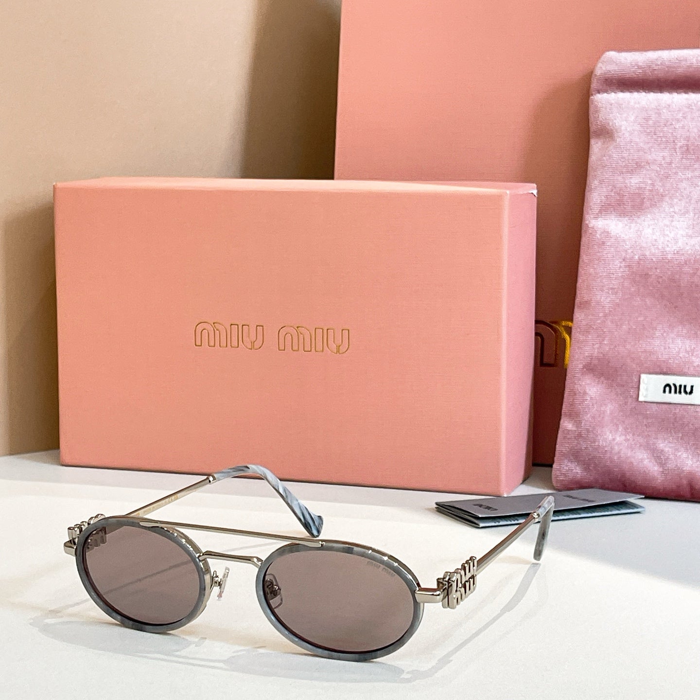 Miu Miu round sunglasses with silver frame, gray tinted lenses, thin arms