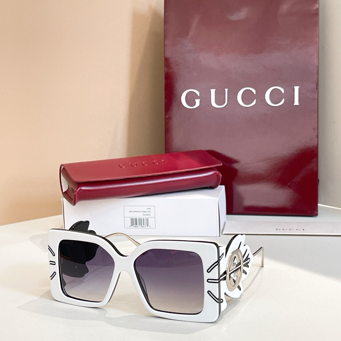 Square white sunglasses with dark lenses and gold logo on side arms