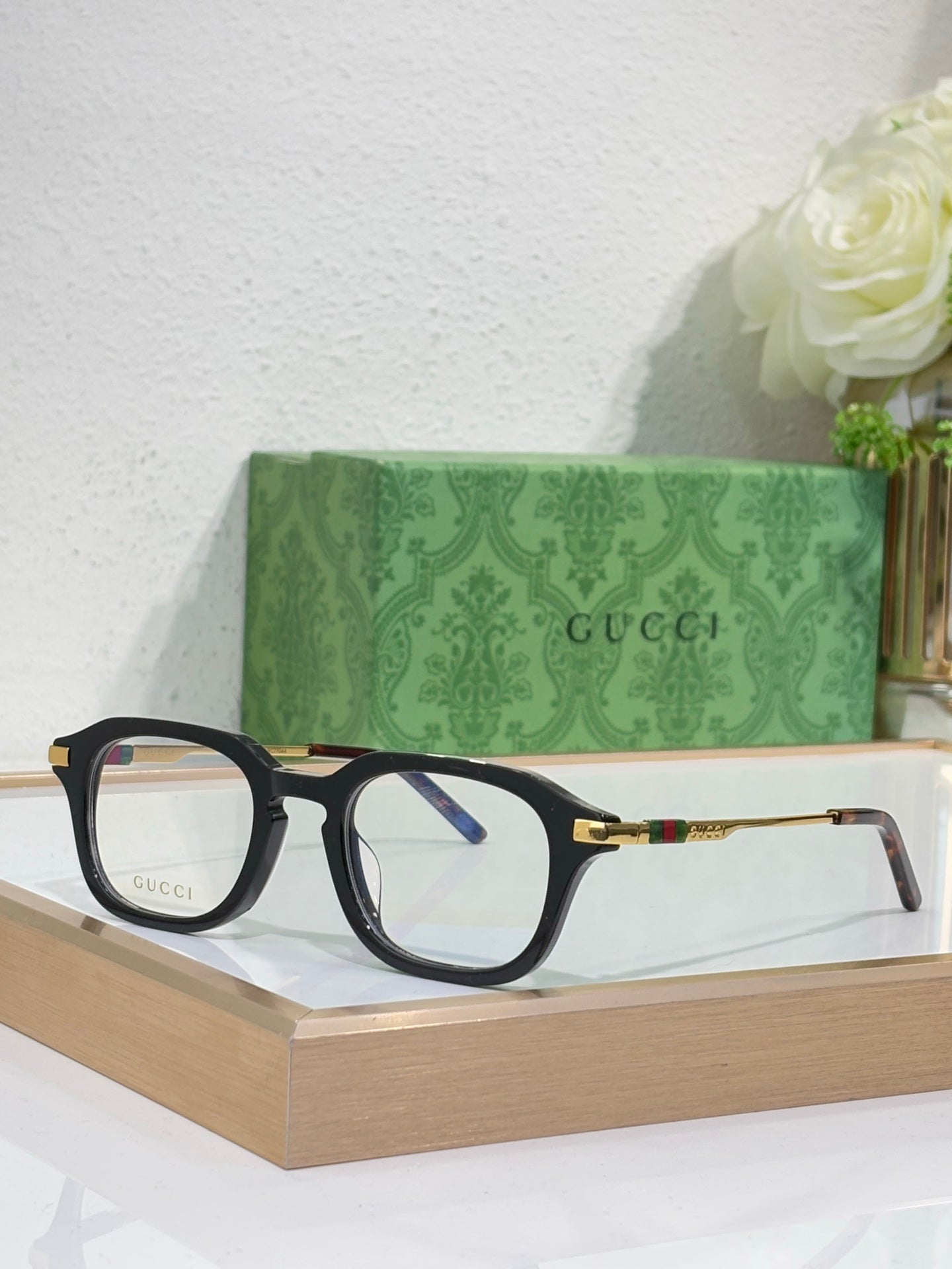Black eyeglasses with clear lenses and gold-toned arm details.