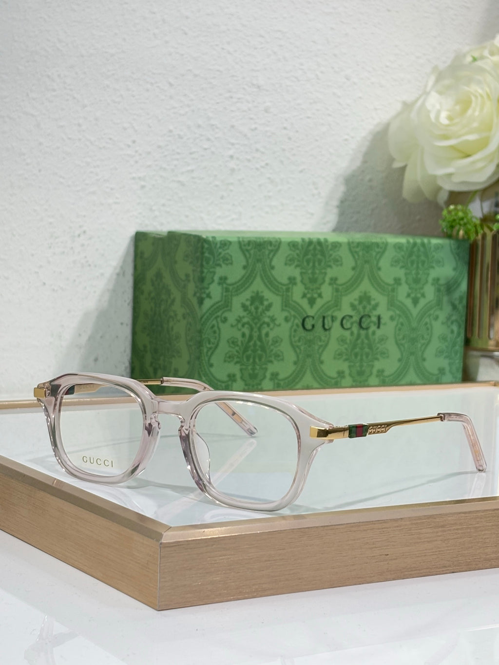Light-pink translucent eyeglasses with clear lenses and gold-toned arm details.
