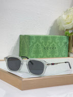 Silver-gray round eyeglasses with dark tinted lenses and gold-toned arm detail.