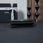 Chanel flap bag in black leather, side view with gold-toned clasp and chain
