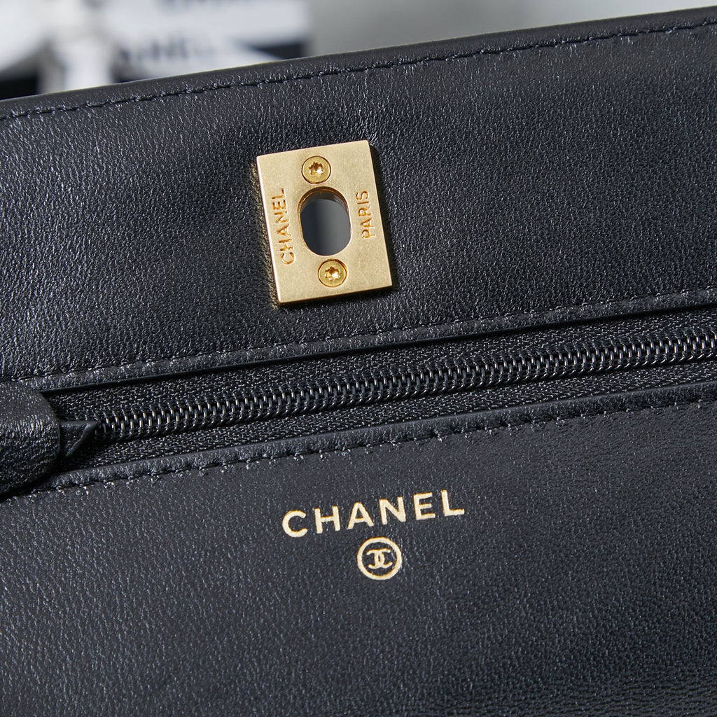 Chanel logo plate and zipper on black leather flap bag, gold-tone hardware
