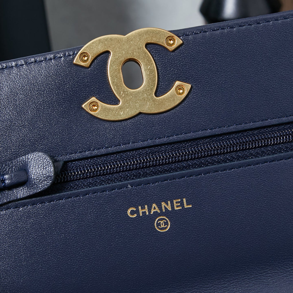 Chanel navy blue bag close-up with gold CC logo and zipper edge.