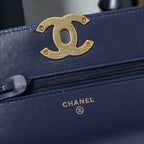 Chanel navy blue bag close-up with gold CC logo and zipper edge.