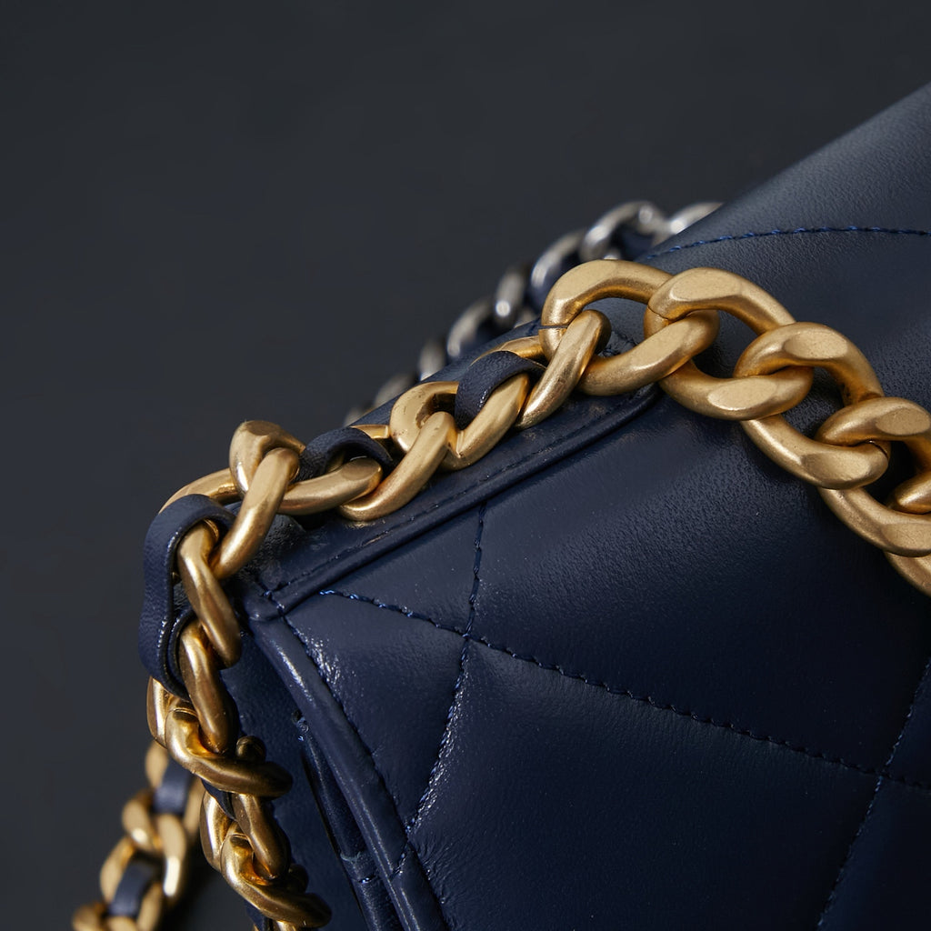 Chanel quilted navy blue bag edge with gold-and-black chain strap.