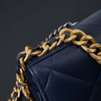 Chanel quilted navy blue bag edge with gold-and-black chain strap.