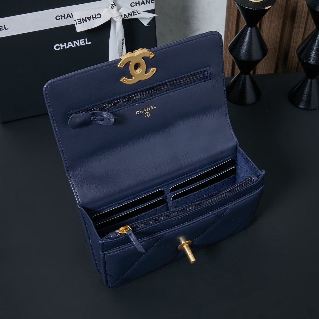 Chanel wallet-style bag in navy blue with gold CC clasp and ribbon detail.