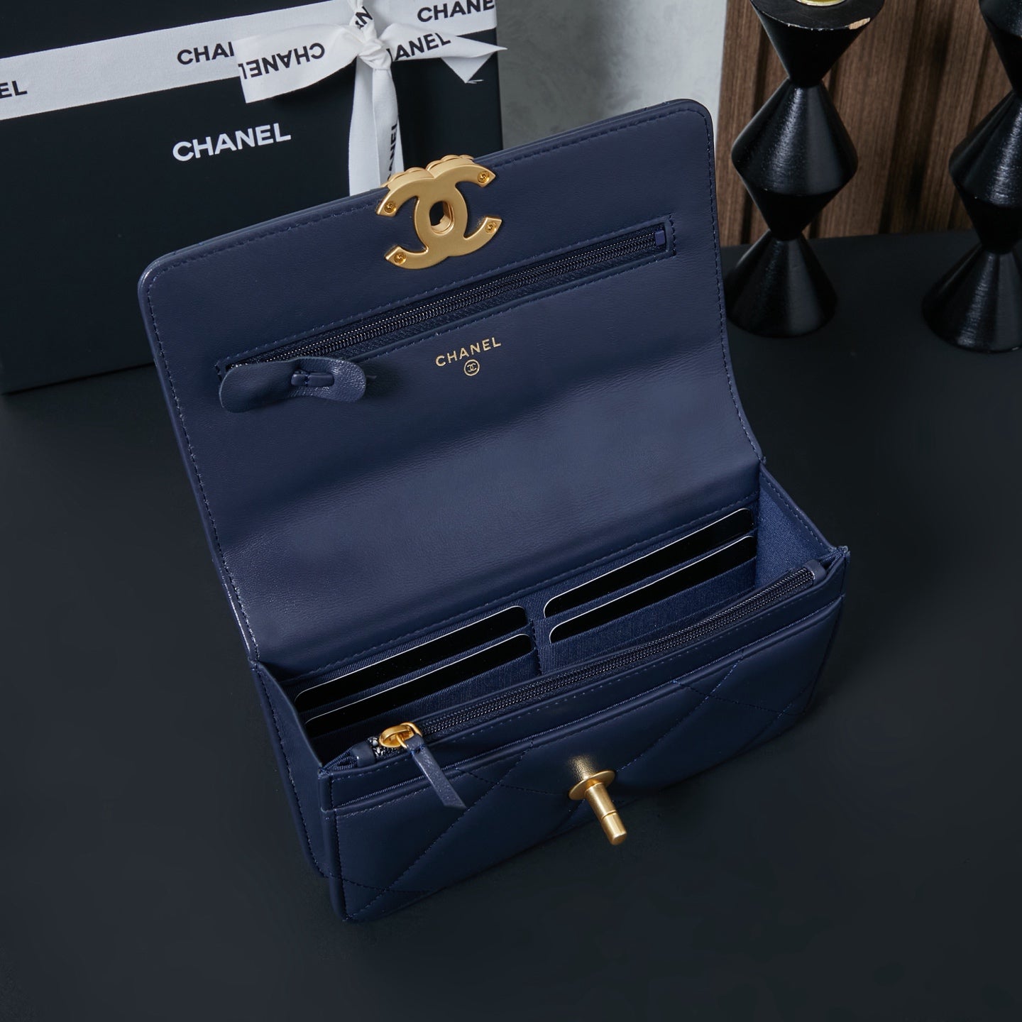 Chanel wallet-style bag in navy blue with gold CC clasp and ribbon detail.