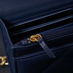 Chanel interior close-up with navy lining and gold chain pull on zipper.