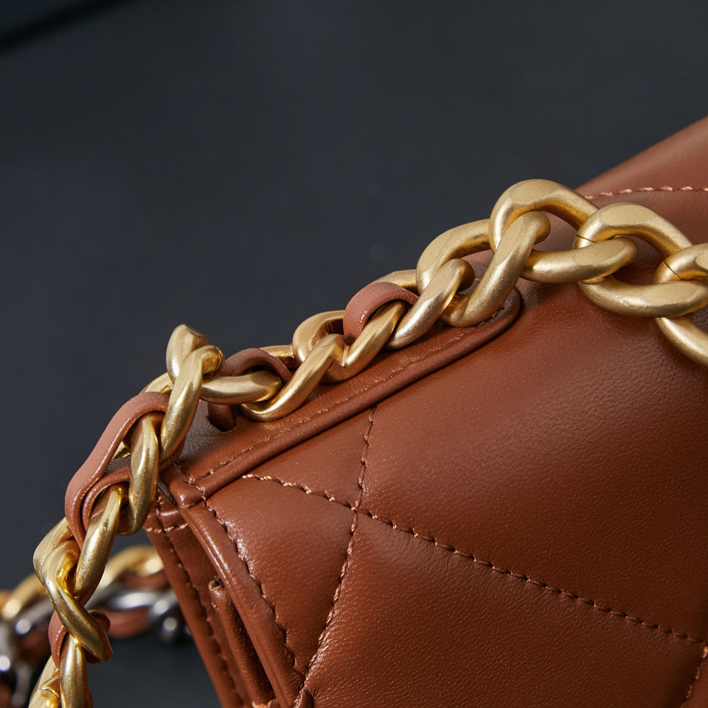 Chanel bag close-up of gold chain strap and stitched tan-brown edge