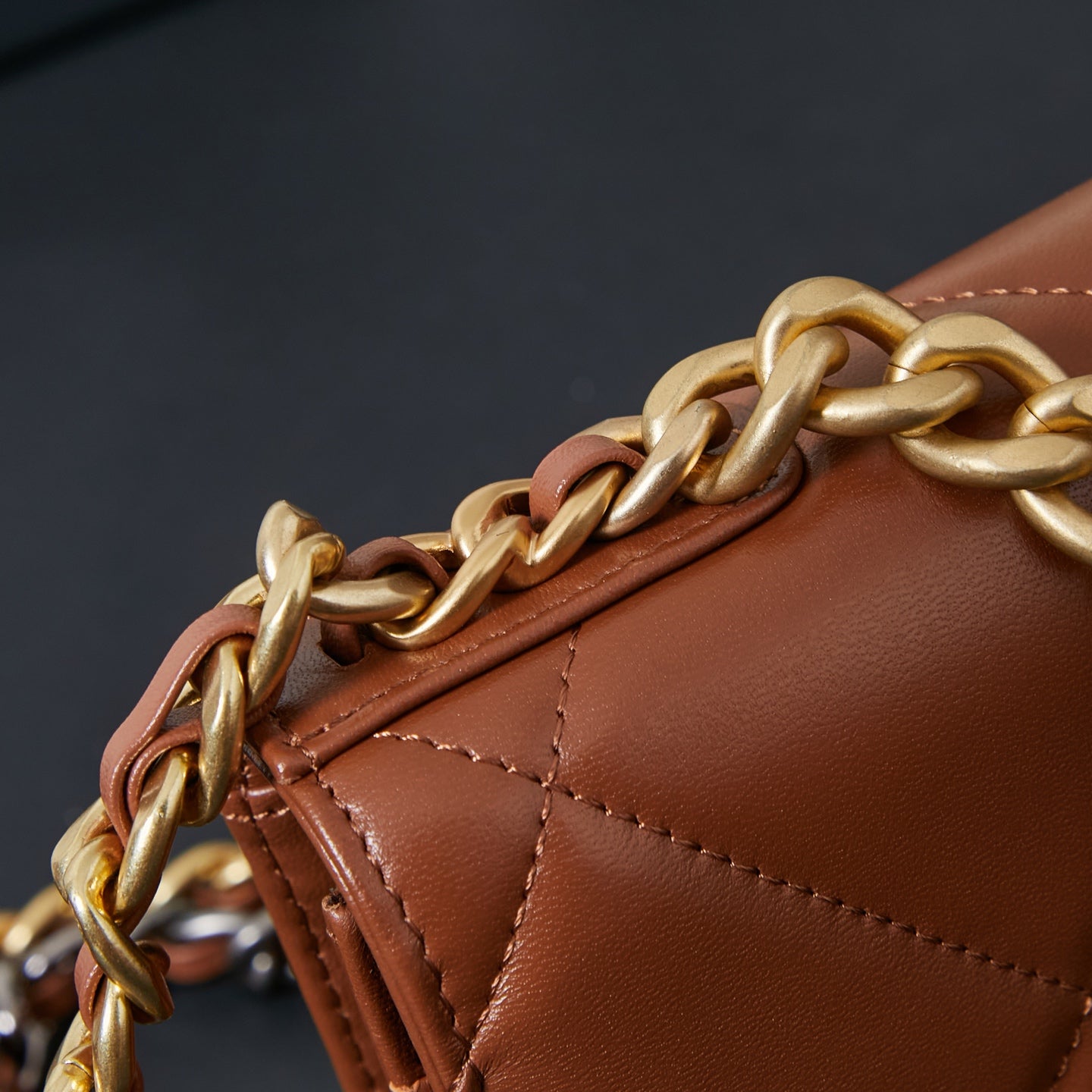 Chanel bag close-up of gold chain strap and stitched tan-brown edge