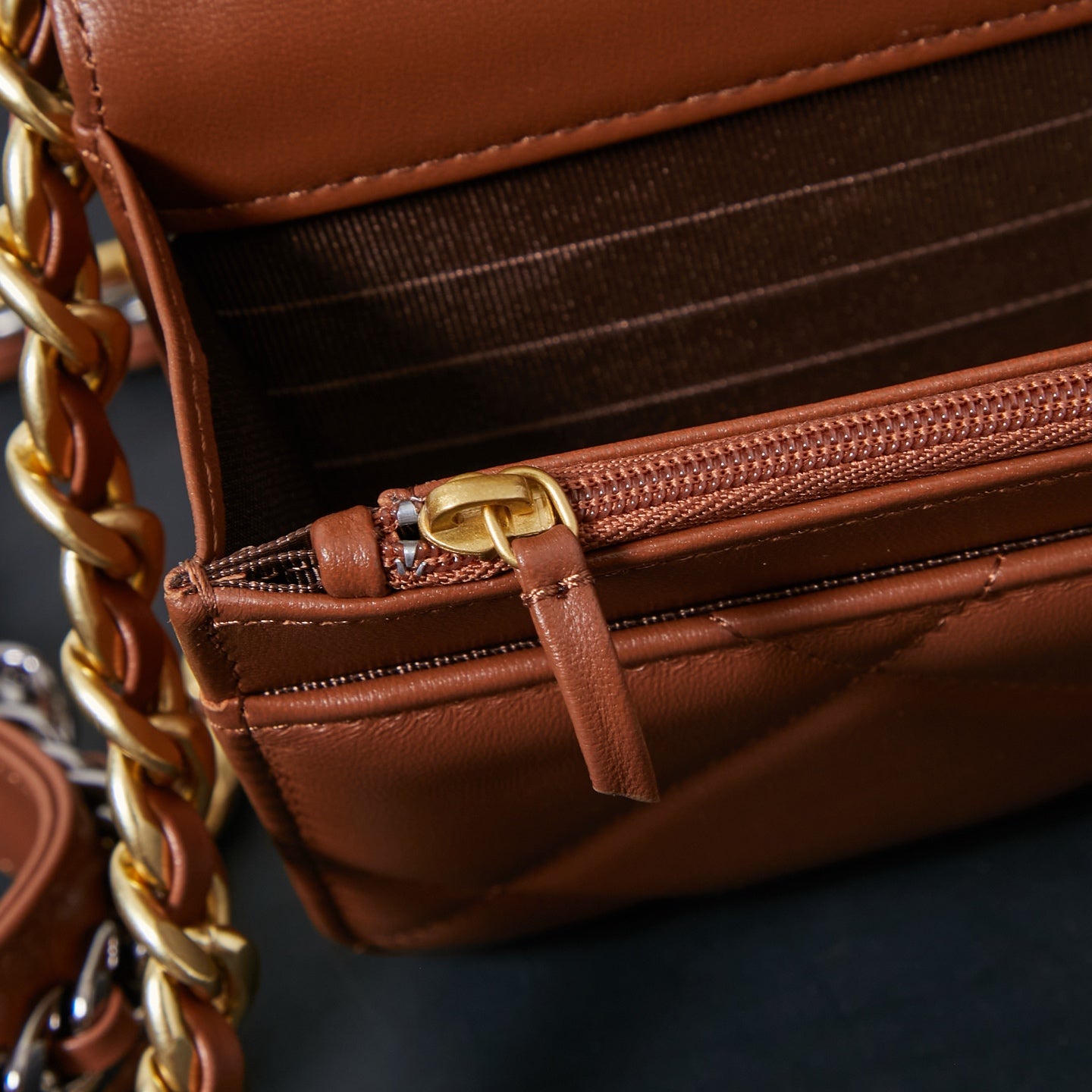 Chanel bag close-up of interior zipper pocket with brown leather tab pull