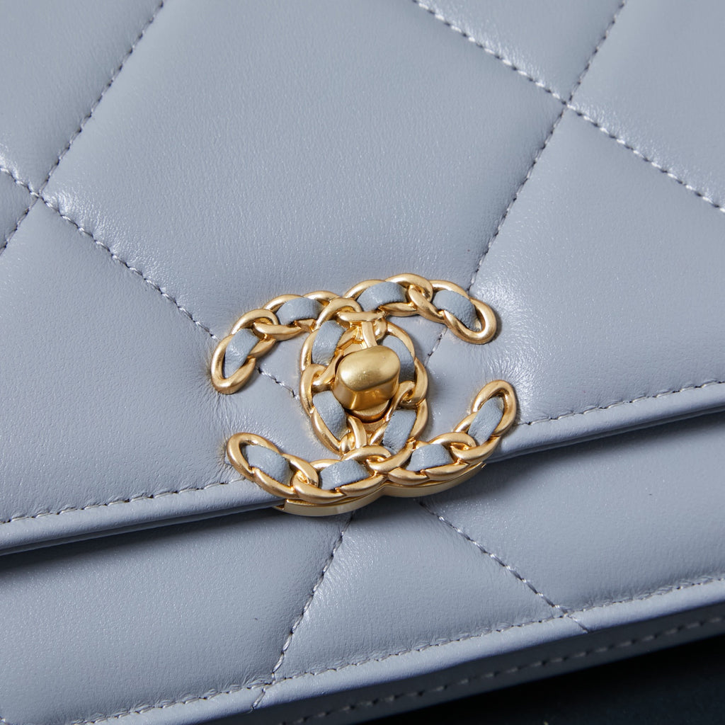 Light blue quilted flap bag with gold chain link detail on the front