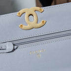 Light blue flap bag with gold interlocking CC logo and front zipper pocket