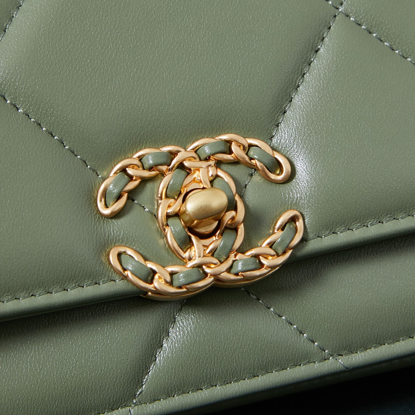Olive green Chanel flap bag close-up of gold-tone chain and stitched quilting