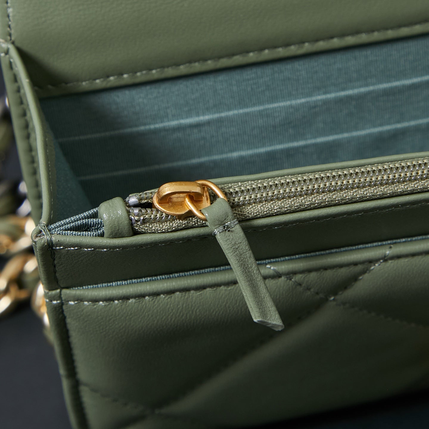 Olive green Chanel bag interior with dark pocket lining and gold-tone zipper pull
