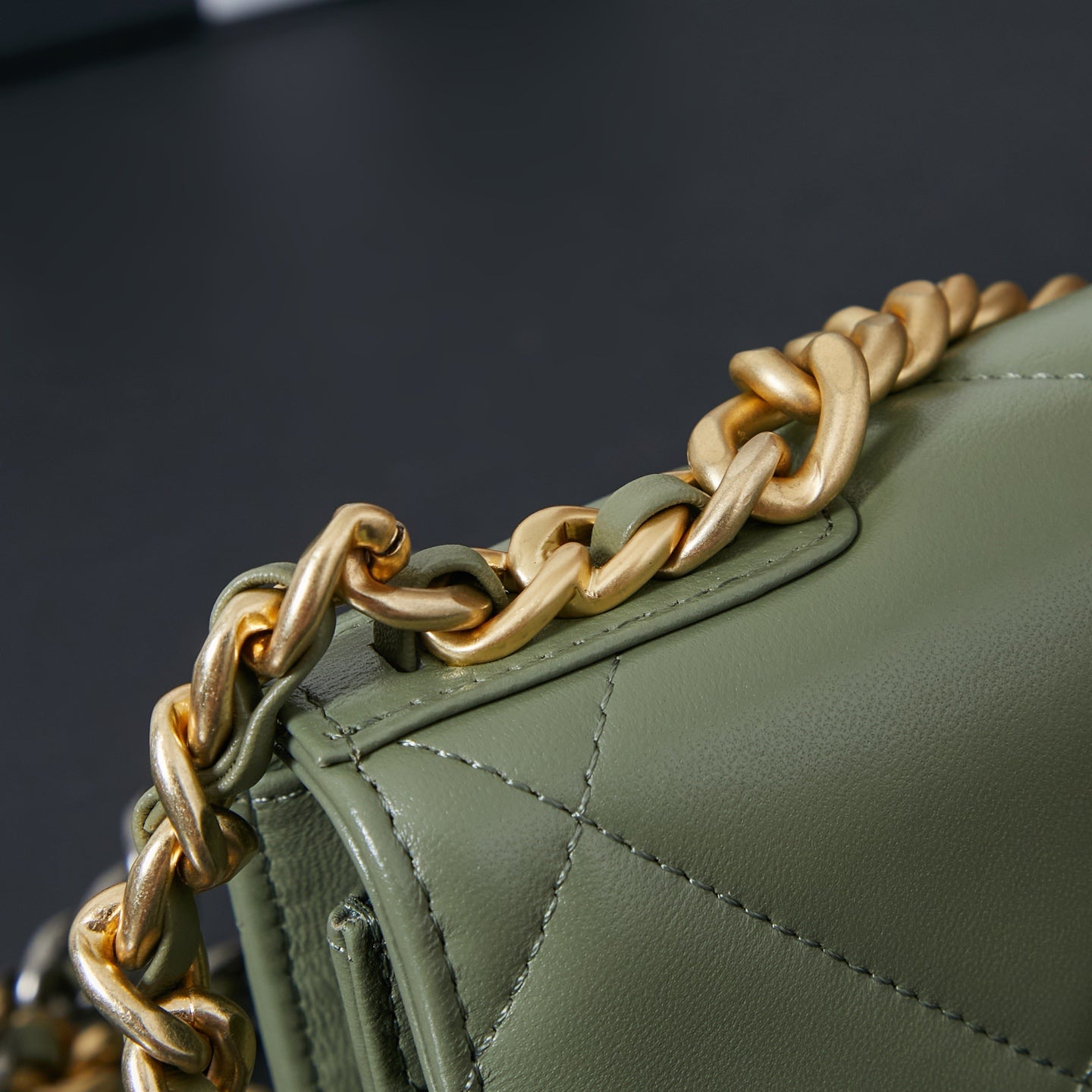 Gold-tone chain on olive green Chanel flap bag with stitched edge trim