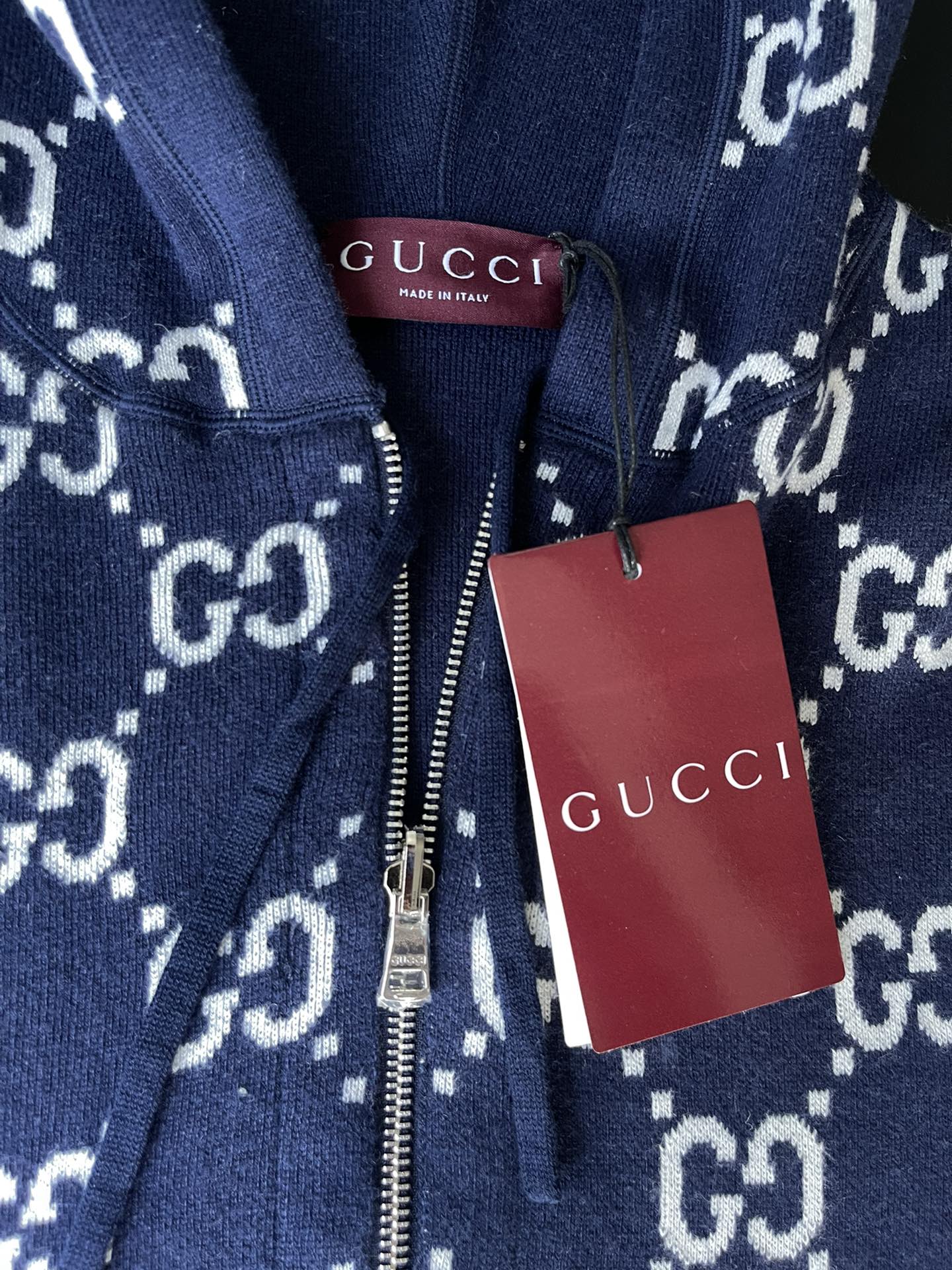 Navy GG-pattern hoodie with front zip and white Gucci hang tag
