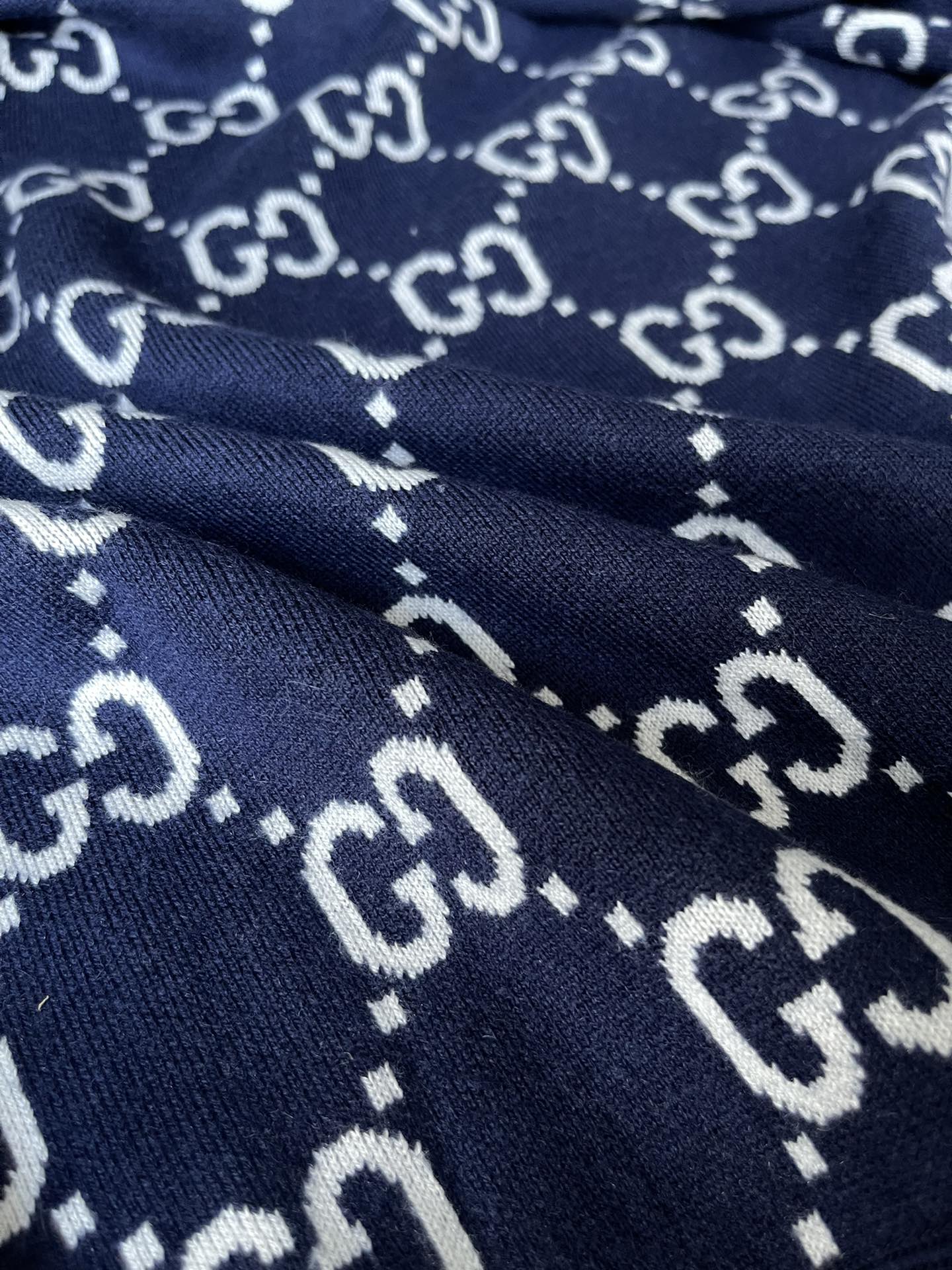 Navy knit hoodie with repeating GG monogram pattern detail