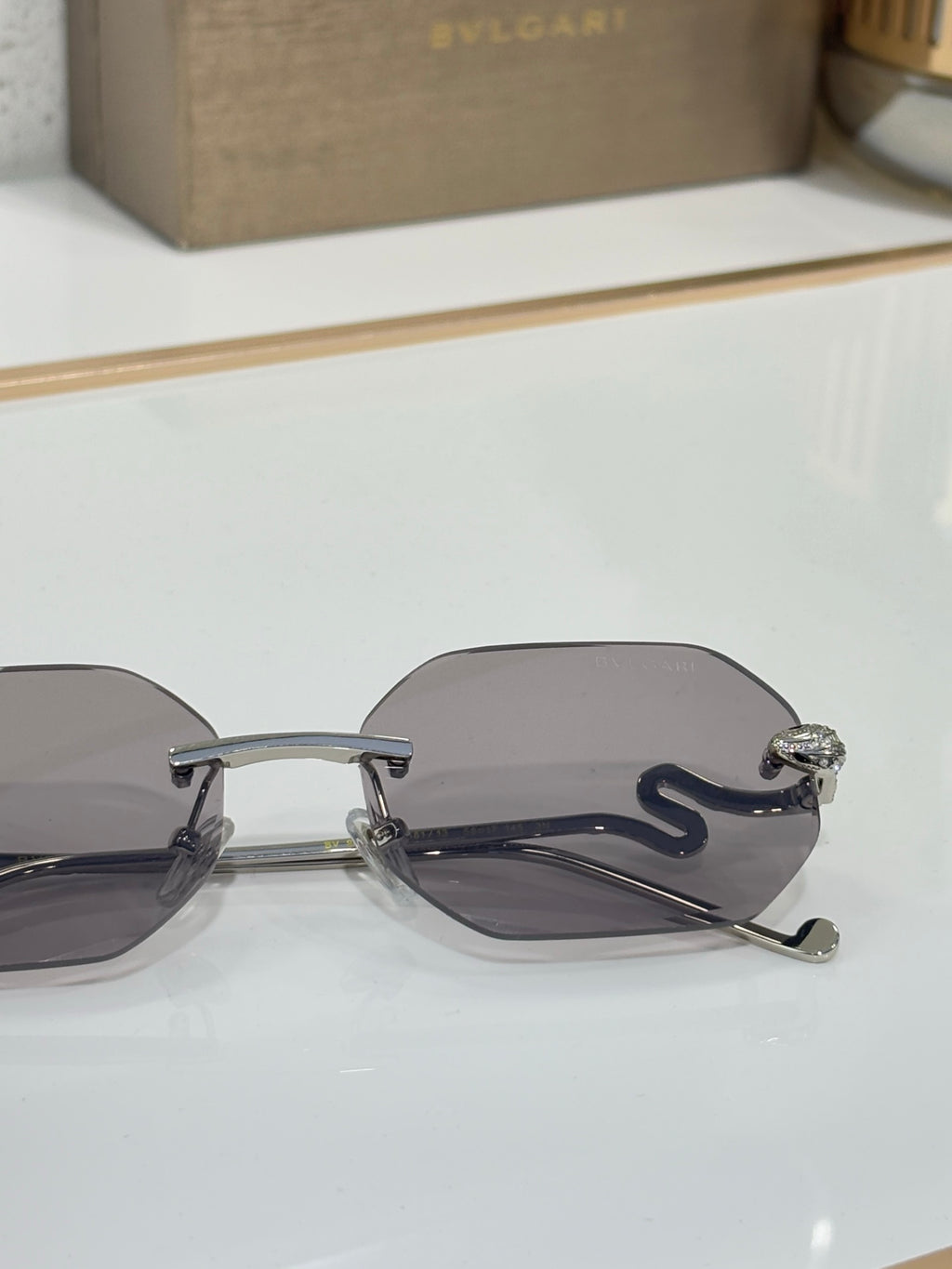 Bvlgari sunglasses close-up: dark lenses, silver-tone frame, ornate temple detail