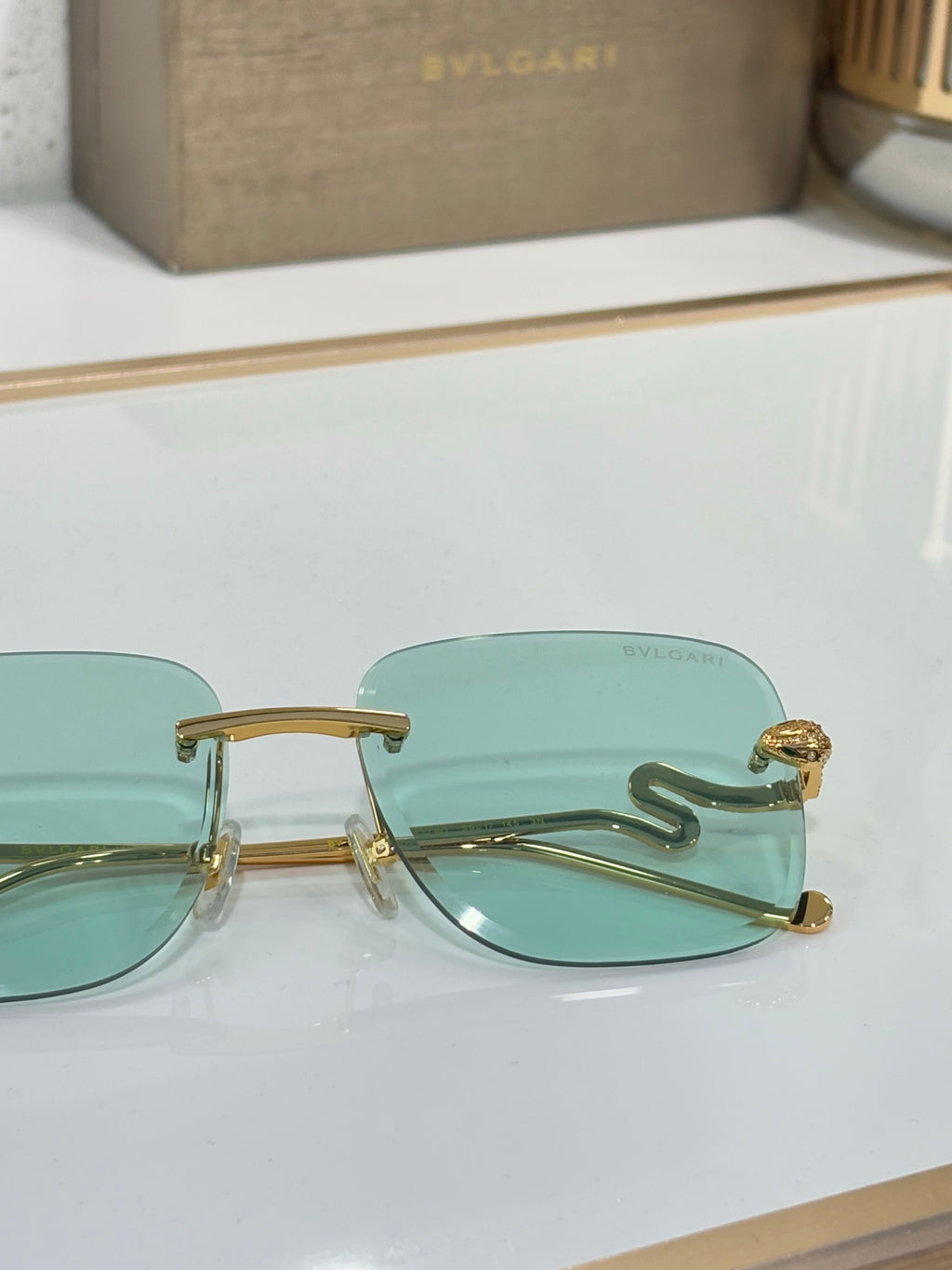 Bvlgari round sunglasses with gold frame and teal gradient lenses, close-up