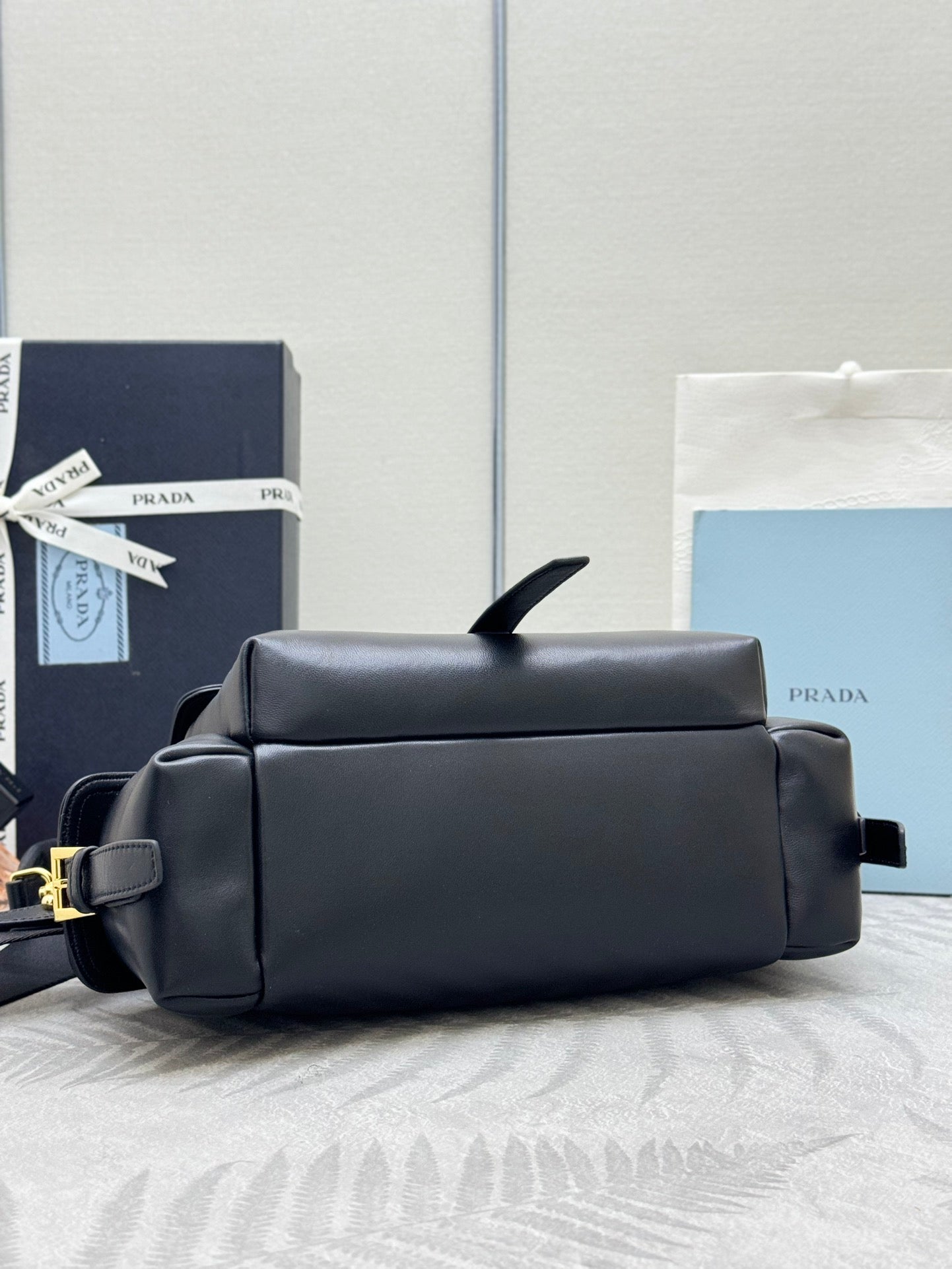 Black Prada shoulder bag with flap top and gold-tone hardware, shown from back angle