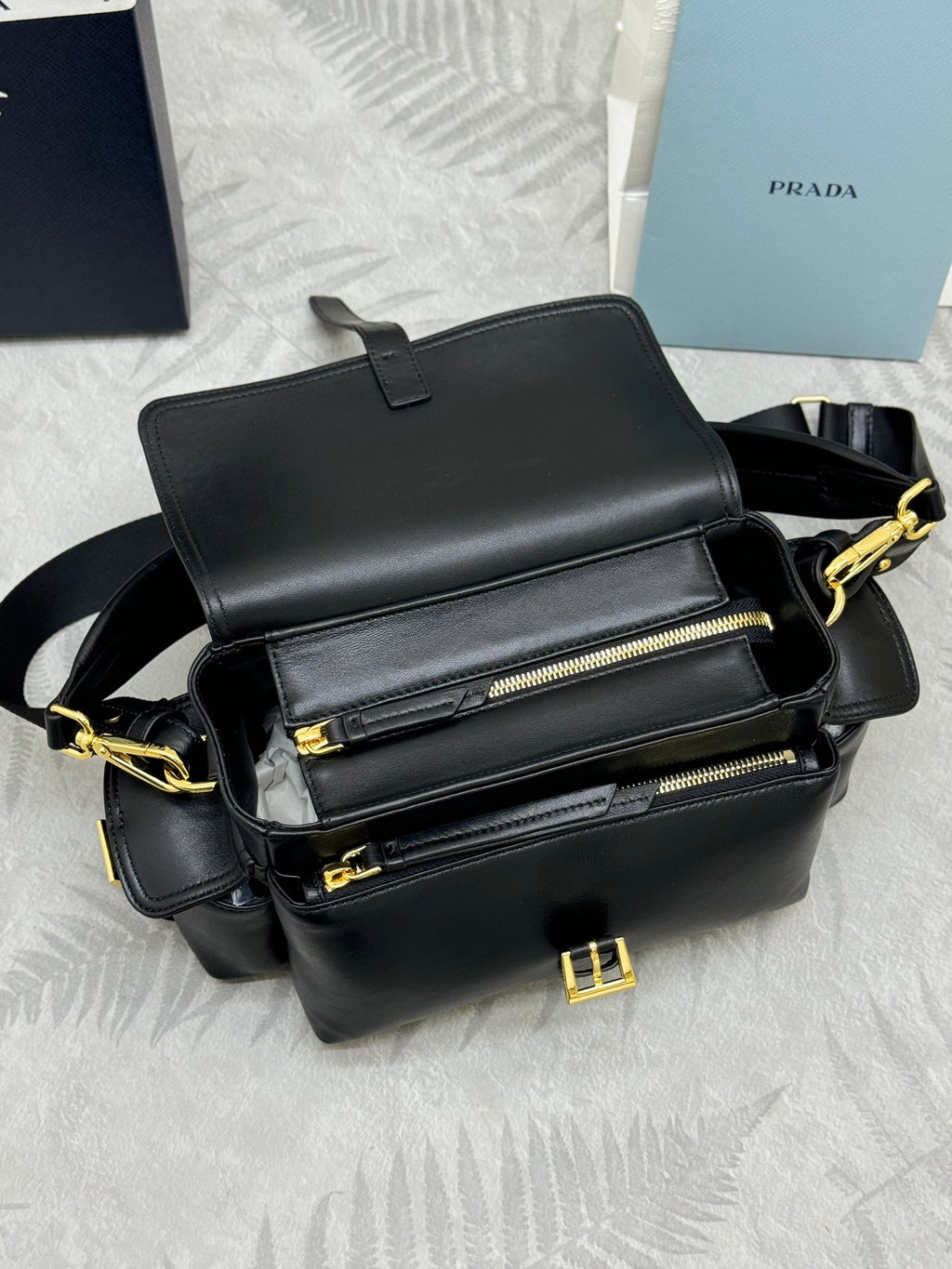 Black leather crossbody bag with flap, front zippers, and gold-tone hardware details