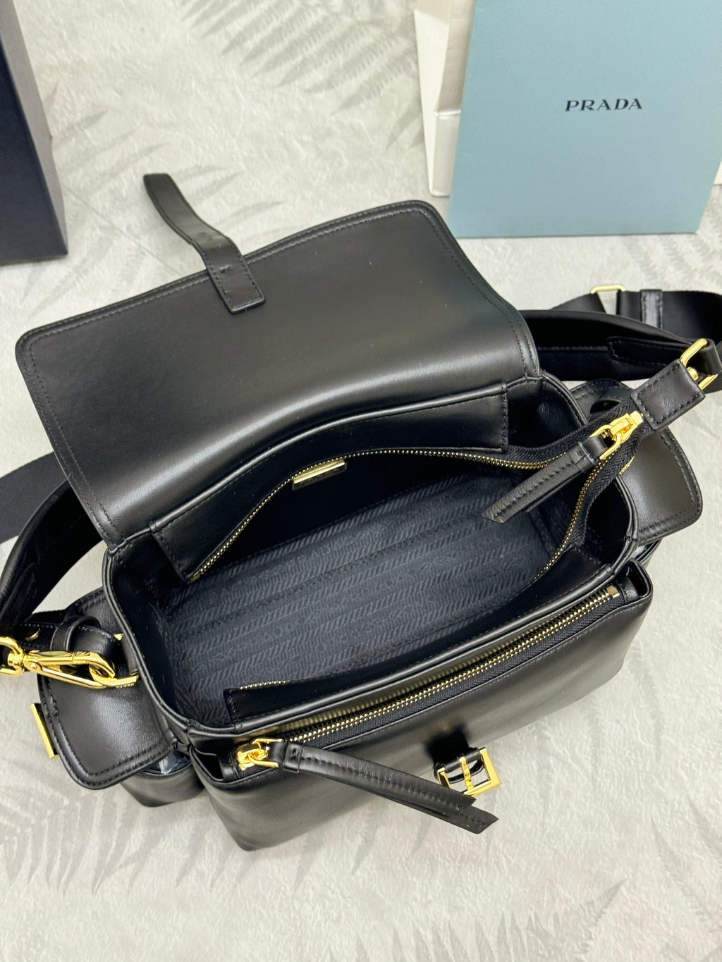 Black leather crossbody bag with front zip pocket and gold-tone zippers and chain strap
