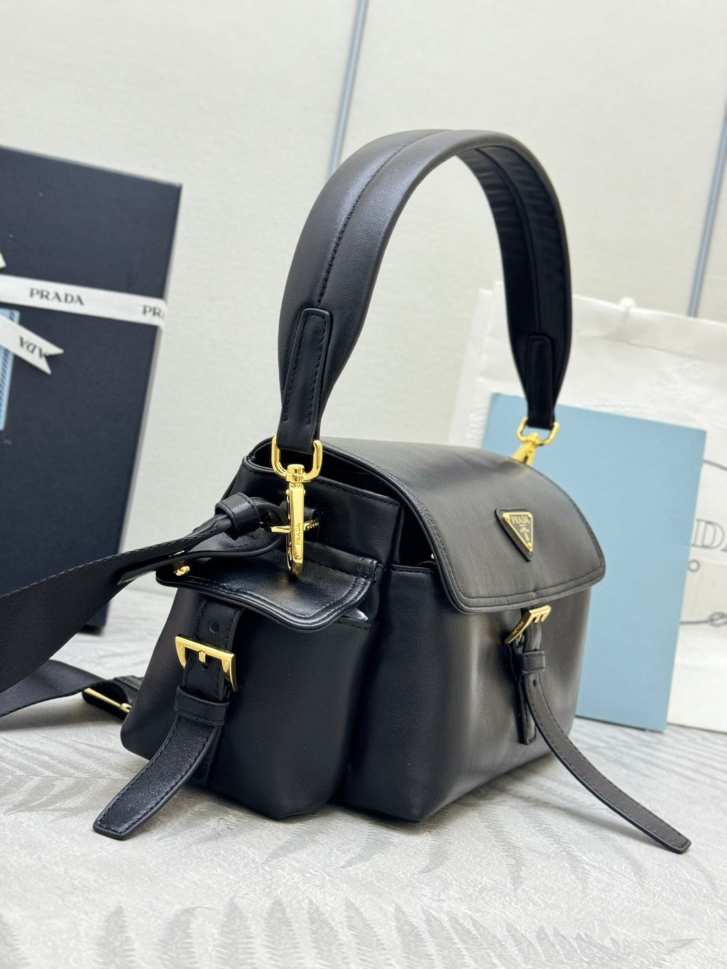 Black leather top-handle shoulder bag with gold-tone hardware and logo detail on flap