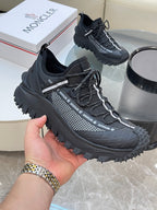 Black Moncler lace-up sneakers, hand holding front shoe