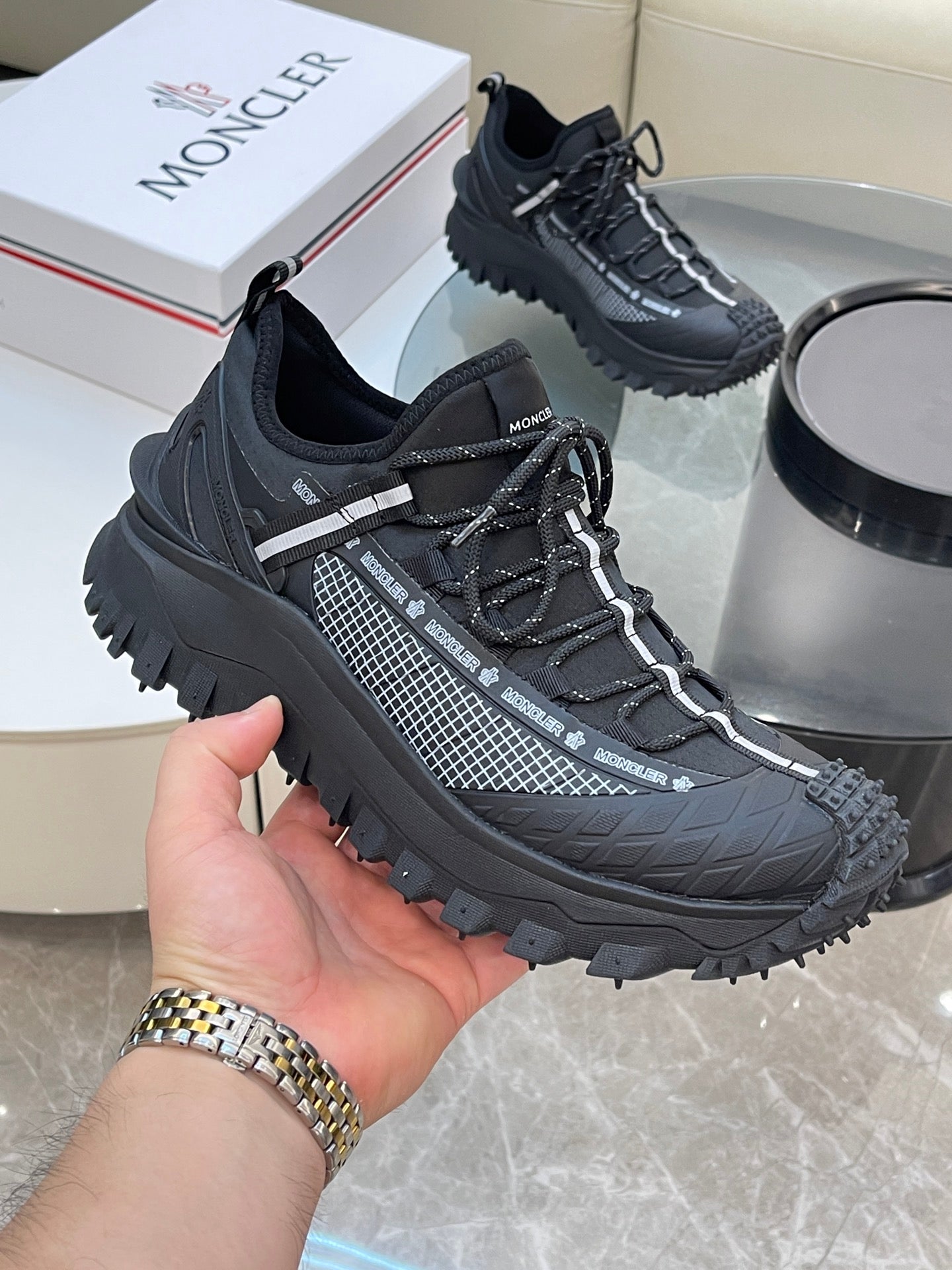 Black Moncler lace-up sneakers, hand holding front shoe