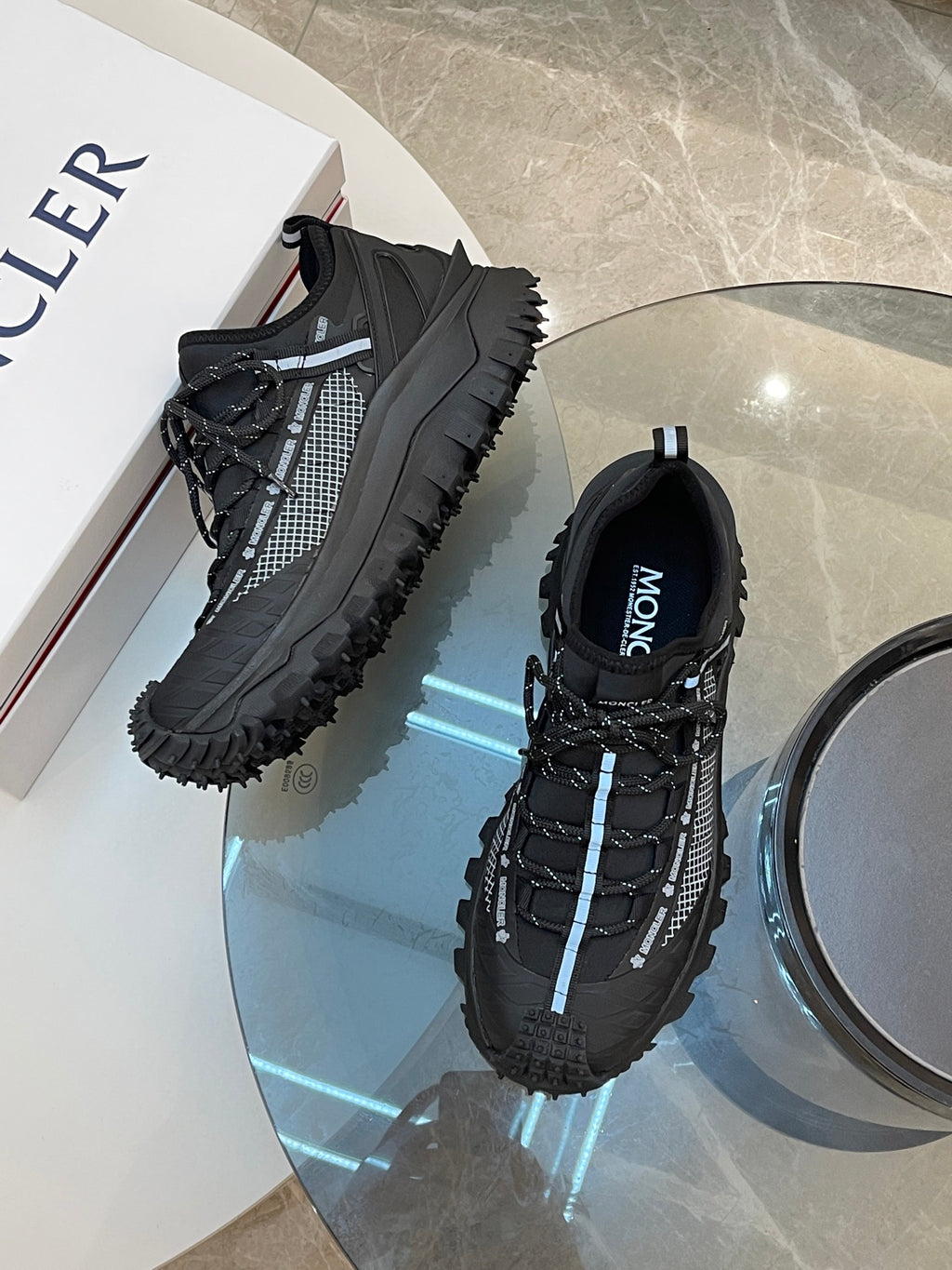 Black Moncler lace-up sneakers with chunky tread and blue-striped accents