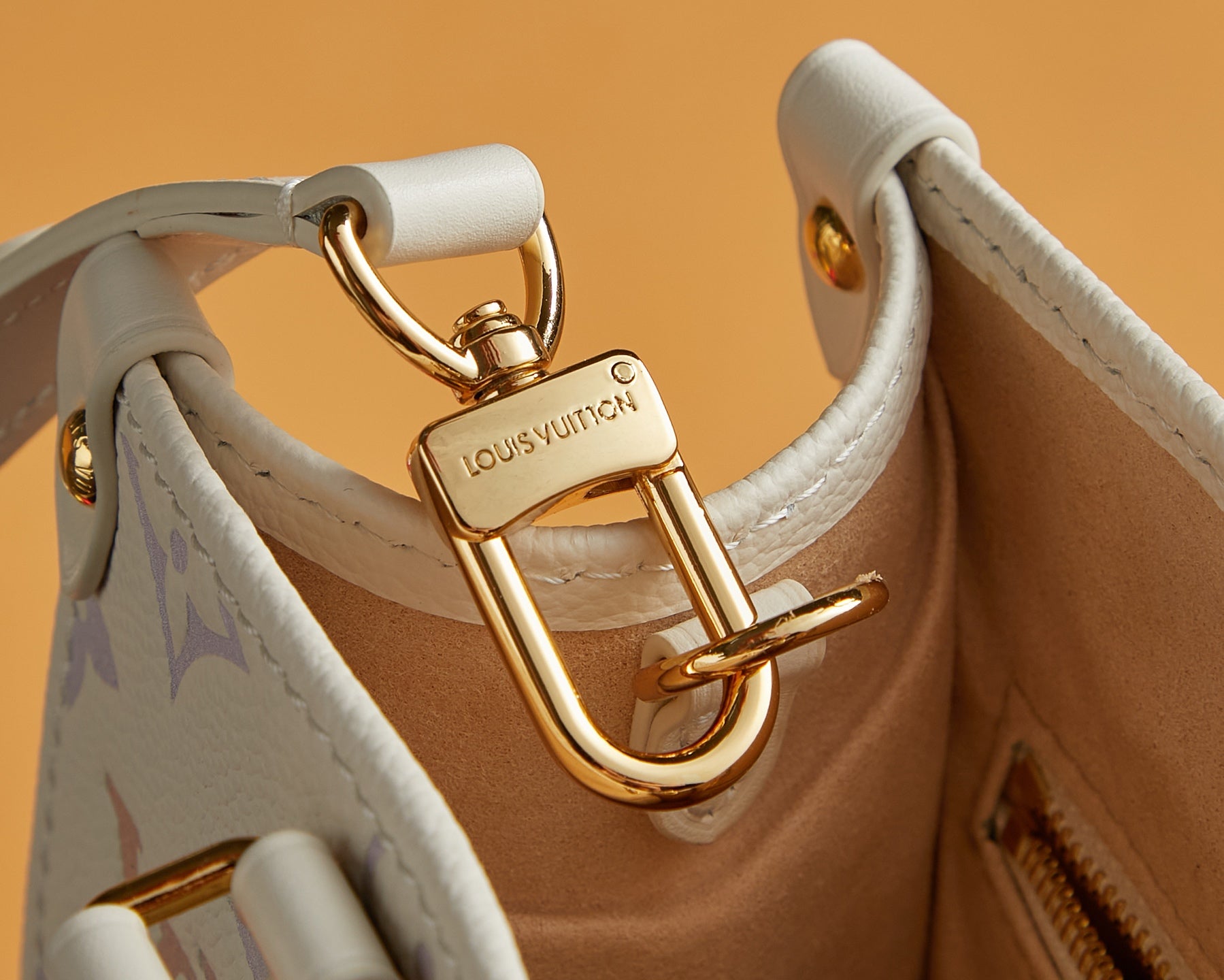 Gold-tone D-ring clasp on Louis Vuitton tote bag with white strap